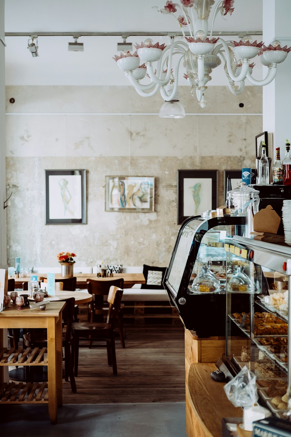 Vitrina de cafetería llena de pasteles y mesas rústicas de madera.