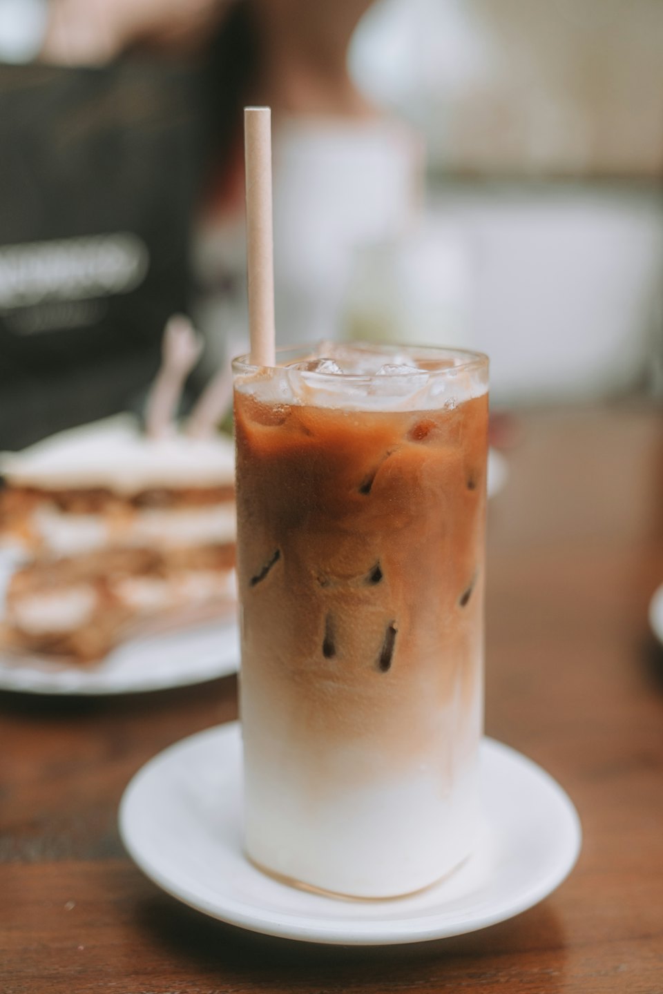 Café helado con capas de leche en un vaso transparente con pajita.