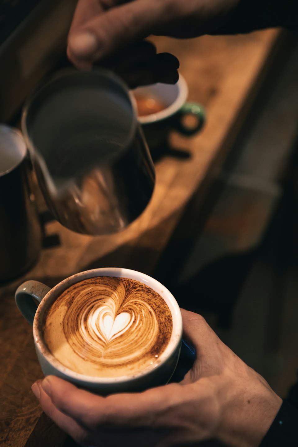 Un barista vierte leche vaporizada en una taza de café.